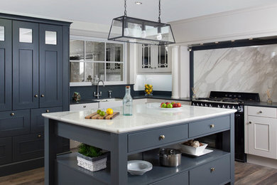 Inspiration for a large transitional l-shaped eat-in kitchen in Other with a farmhouse sink, beaded inset cabinets, grey cabinets, marble benchtops, grey splashback, marble splashback, black appliances, medium hardwood floors, with island and brown floor.