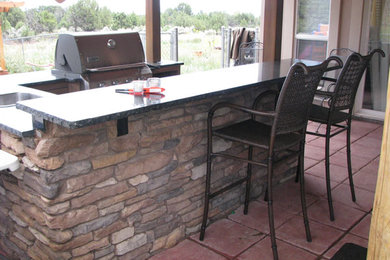 Large backyard stone patio kitchen photo in Albuquerque