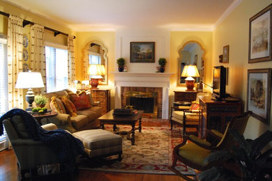 Inspiration for a mid-sized traditional family room in DC Metro with yellow walls, dark hardwood floors, a standard fireplace, a wood fireplace surround and a freestanding tv.