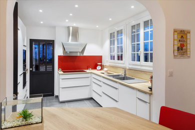 Cette photo montre une cuisine avec des portes de placard blanches, un plan de travail en stratifié, une crédence rouge, une crédence en feuille de verre et un plan de travail beige.