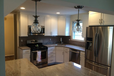 Open concept kitchen - small traditional l-shaped ceramic tile open concept kitchen idea in Baltimore with an undermount sink, white cabinets, granite countertops, gray backsplash, glass tile backsplash, stainless steel appliances, an island and shaker cabinets