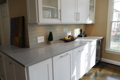Example of a transitional l-shaped dark wood floor open concept kitchen design in Baltimore with a single-bowl sink, shaker cabinets, white cabinets, quartzite countertops, gray backsplash, glass tile backsplash, stainless steel appliances and an island