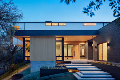 Inspiration for a 1960s multicolored two-story mixed siding exterior home remodel in Austin with a metal roof and a black roof