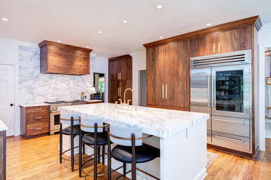 Example of a mid-sized transitional u-shaped medium tone wood floor and brown floor eat-in kitchen design in Raleigh with an undermount sink, flat-panel cabinets, medium tone wood cabinets, marble countertops, white backsplash, marble backsplash, stainless steel appliances, an island and white countertops