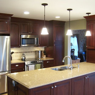 Large kitchen pantry inspiration - Large u-shaped kitchen pantry photo in Burlington with a drop-in sink, recessed-panel cabinets, medium tone wood cabinets, granite countertops, white backsplash and an island