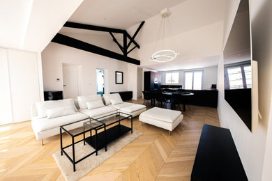 Ejemplo de salón abierto moderno grande con paredes blancas, suelo de madera clara, televisor colgado en la pared, suelo beige y vigas vistas