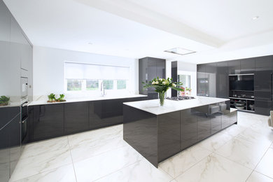 Large modern l-shaped open plan kitchen in Surrey with an undermount sink, flat-panel cabinets, grey cabinets, solid surface benchtops, white splashback, black appliances, ceramic floors, with island, white floor and white benchtop.