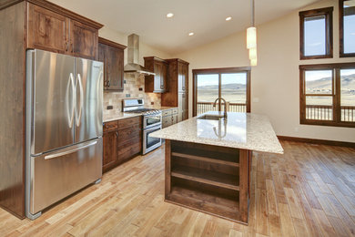 Open concept kitchen - mid-sized transitional single-wall medium tone wood floor and beige floor open concept kitchen idea in Denver with a single-bowl sink, shaker cabinets, medium tone wood cabinets, granite countertops, beige backsplash, limestone backsplash, stainless steel appliances and an island