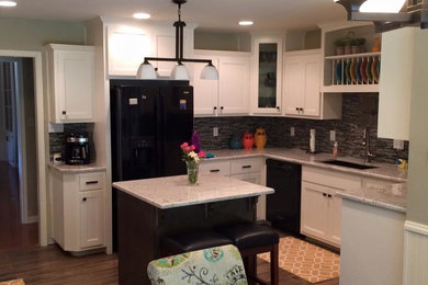 Inspiration for a mid-sized timeless u-shaped medium tone wood floor and brown floor kitchen remodel in Dallas with an undermount sink, shaker cabinets, white cabinets, granite countertops, brown backsplash, matchstick tile backsplash, black appliances and an island
