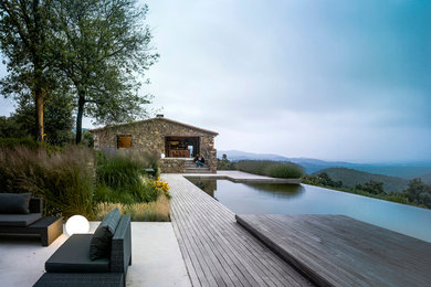 Inspiration for an expansive country backyard custom-shaped infinity pool in Barcelona with a water feature and decking.