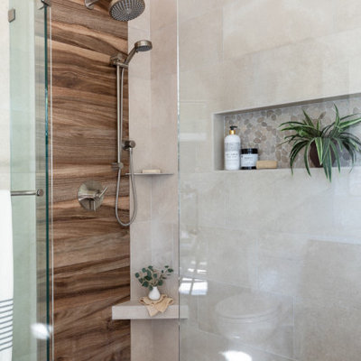 Mid-sized island style master beige tile and ceramic tile ceramic tile, gray floor and double-sink corner shower photo in San Francisco with louvered cabinets, medium tone wood cabinets, a two-piece toilet, beige walls, an undermount sink, solid surface countertops, a hinged shower door, white countertops, a niche and a built-in vanity