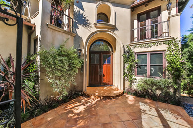 Example of a tuscan beige two-story stucco house exterior design in Los Angeles with a tile roof