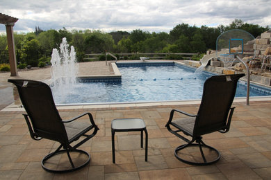 Inspiration for a large rustic backyard concrete paver and l-shaped pool fountain remodel in Milwaukee