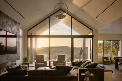 Example of a large trendy open concept light wood floor and beige floor living room design in Austin with white walls, a standard fireplace, a plaster fireplace and a wall-mounted tv