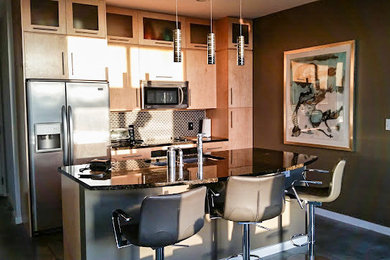 Example of a small minimalist single-wall concrete floor eat-in kitchen design in Austin with an undermount sink, flat-panel cabinets, light wood cabinets, granite countertops, brown backsplash, ceramic backsplash, stainless steel appliances and an island