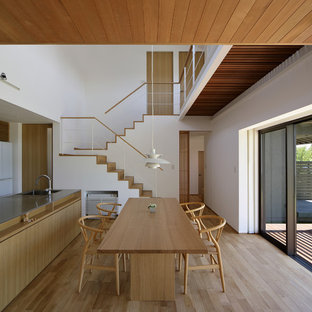 Immagine di una sala da pranzo aperta verso la cucina etnica con pareti bianche, pavimento in legno massello medio e pavimento marrone