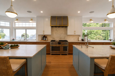 Open concept kitchen - huge coastal l-shaped light wood floor and brown floor open concept kitchen idea in Seattle with an undermount sink, recessed-panel cabinets, medium tone wood cabinets, quartz countertops, quartz backsplash, paneled appliances, two islands and white countertops