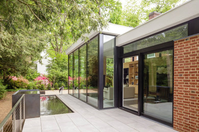 Large minimalist red three-story brick exterior home photo in Other with a white roof