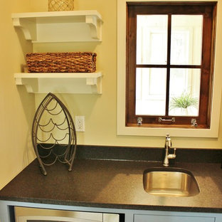 Small beach style kitchen pantry remodeling - Inspiration for a small beach style single-wall slate floor kitchen pantry remodel in Grand Rapids with a farmhouse sink, shaker cabinets, blue cabinets, granite countertops, gray backsplash, stone tile backsplash, stainless steel appliances and an island