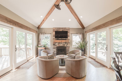 Family room - mid-sized transitional enclosed light wood floor and beige floor family room idea in Detroit with beige walls, a standard fireplace, a stone fireplace and a wall-mounted tv