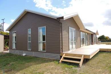 Large contemporary one-storey brown exterior in Christchurch with concrete fiberboard siding and a gable roof.