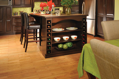 Transitional l-shaped light wood floor eat-in kitchen photo in Other with raised-panel cabinets, dark wood cabinets, green backsplash, stainless steel appliances and an island