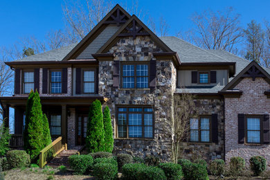 Modelo de fachada de casa gris y gris de estilo americano grande de dos plantas con revestimiento de piedra, tejado a cuatro aguas, tejado de teja de madera y panel y listón
