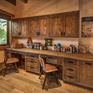 Immagine di uno studio rustico con pareti beige, parquet scuro e scrivania incassata