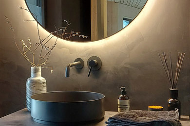 Geräumige Moderne Fliesenlose Dusche mit schwarzen Schränken, bodengleicher Dusche, Wandtoilette mit Spülkasten, grauer Wandfarbe, Aufsatzwaschbecken, offener Dusche, schwarzer Waschtischplatte, Einzelwaschbecken und schwebendem Waschtisch in Frankfurt am Main