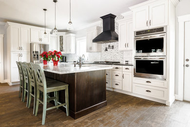 Example of a large transitional l-shaped medium tone wood floor open concept kitchen design in Miami with an undermount sink, shaker cabinets, white cabinets, marble countertops, multicolored backsplash, matchstick tile backsplash, stainless steel appliances and an island