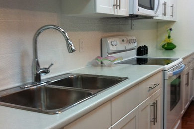 Example of a trendy medium tone wood floor eat-in kitchen design in Other with a double-bowl sink, laminate countertops, white backsplash, porcelain backsplash and white appliances
