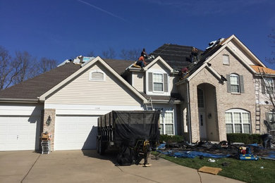 Inspiration for a large contemporary two-story house exterior remodel in St Louis with a hip roof and a shingle roof