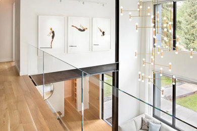 Idée de décoration pour un couloir design de taille moyenne avec un mur blanc et un sol en bois brun.