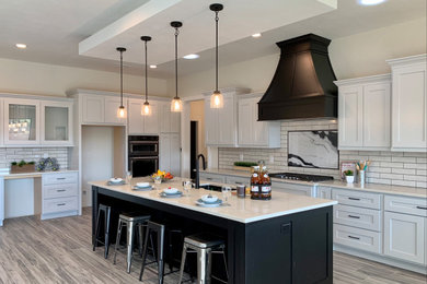 Inspiration for a large contemporary l-shaped ceramic tile and gray floor open concept kitchen remodel in Albuquerque with an undermount sink, recessed-panel cabinets, white cabinets, quartz countertops, white backsplash, subway tile backsplash, stainless steel appliances, an island and white countertops