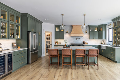 Inspiration for a large timeless u-shaped light wood floor and beige floor open concept kitchen remodel in Detroit with a farmhouse sink, shaker cabinets, green cabinets, quartz countertops, white backsplash, marble backsplash, stainless steel appliances, an island and white countertops