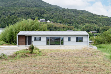 Imagen de fachada de casa minimalista de una planta con tejado a dos aguas y tejado de metal
