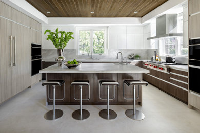 Inspiration for a large contemporary u-shaped porcelain tile and gray floor enclosed kitchen remodel in New York with an undermount sink, flat-panel cabinets, brown cabinets, marble countertops, gray backsplash, marble backsplash, paneled appliances, an island and gray countertops
