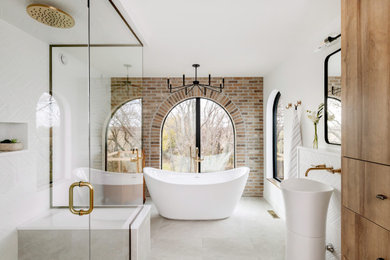 This is an example of a large eclectic master bathroom in Other with flat-panel cabinets, medium wood cabinets, a freestanding tub, a double shower, a one-piece toilet, white tile, ceramic tile, white walls, cement tiles, a pedestal sink, engineered quartz benchtops, white floor, a hinged shower door, white benchtops, a shower seat, a double vanity, a freestanding vanity and brick walls.