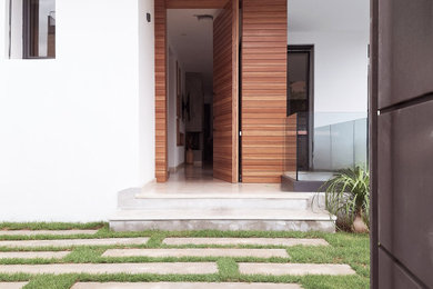 Réalisation d'une porte d'entrée design de taille moyenne avec un mur blanc, un sol en marbre, une porte pivot, une porte en bois clair, un sol beige et du lambris de bois.