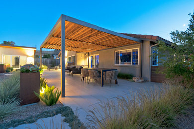 Imagen de patio minimalista grande en patio trasero con chimenea, adoquines de hormigón y pérgola