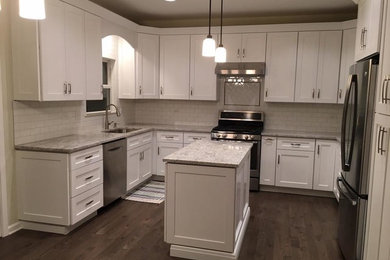 Inspiration for a large transitional u-shaped dark wood floor and brown floor kitchen remodel in Chicago with an undermount sink, shaker cabinets, white cabinets, granite countertops, white backsplash, subway tile backsplash, stainless steel appliances and an island