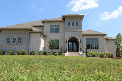 Inspiration for a large mediterranean beige two-story brick exterior home remodel in Nashville with a shingle roof