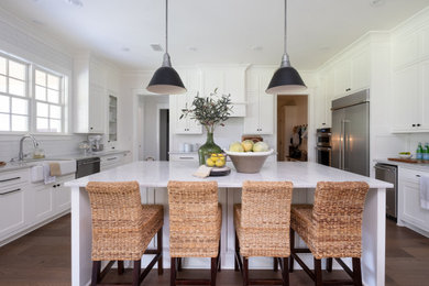 Eat-in kitchen - huge cottage u-shaped medium tone wood floor and brown floor eat-in kitchen idea in Little Rock with a farmhouse sink, shaker cabinets, white cabinets, marble countertops, white backsplash, subway tile backsplash, stainless steel appliances, an island and white countertops