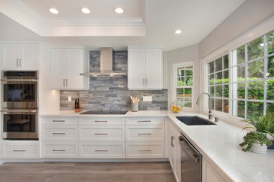 Inspiration for a medium sized modern u-shaped kitchen in Orange County with a submerged sink, shaker cabinets, white cabinets, engineered stone countertops, grey splashback, porcelain splashback, stainless steel appliances, vinyl flooring, an island, grey floors and white worktops.