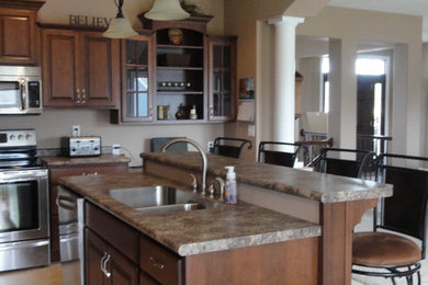 Inspiration for a mid-sized industrial l-shaped open concept kitchen remodel in Other with an undermount sink, raised-panel cabinets, dark wood cabinets, laminate countertops, stainless steel appliances and an island