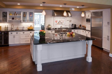 Kitchen - dark wood floor kitchen idea in New York with white cabinets, white backsplash, stainless steel appliances and an island