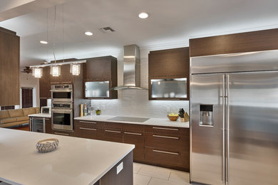 Inspiration for a mid-sized modern l-shaped porcelain tile enclosed kitchen remodel in Miami with a double-bowl sink, flat-panel cabinets, dark wood cabinets, solid surface countertops, white backsplash, glass tile backsplash, stainless steel appliances and a peninsula