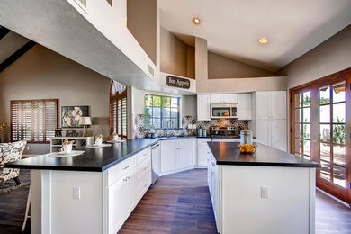 This is an example of a mid-sized contemporary l-shaped eat-in kitchen in Los Angeles with an undermount sink, shaker cabinets, white cabinets, quartzite benchtops, terra-cotta splashback, stainless steel appliances, dark hardwood floors, with island and brown floor.