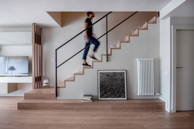 Cette image montre un escalier design en L avec des marches en bois, des contremarches en bois et un garde-corps en métal.