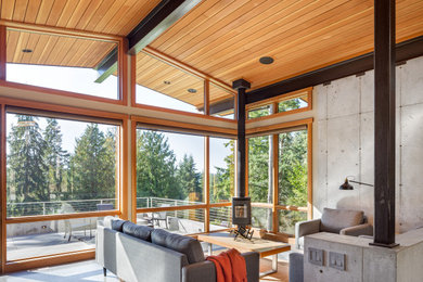 Photo of a mid-sized country enclosed living room in Seattle with concrete floors, a wood stove, no tv and vaulted.